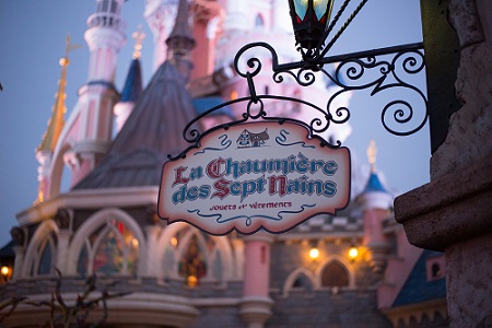 Uithangbord “La Chaumière des Sept Nains” in Fantasyland met het kasteel op de achtergrond – Disneyland Paris