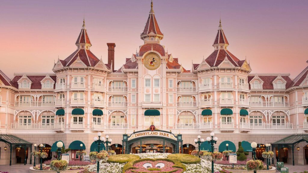 Disneyland Hotel bij de ingang van Disneyland Paris met roze gevel en torentjes in de avondzon