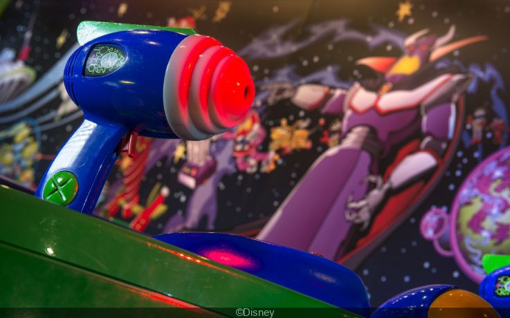 Close-up van laserblaster in Buzz Lightyear Laser Blast met keizer Zurg op de achtergrond
