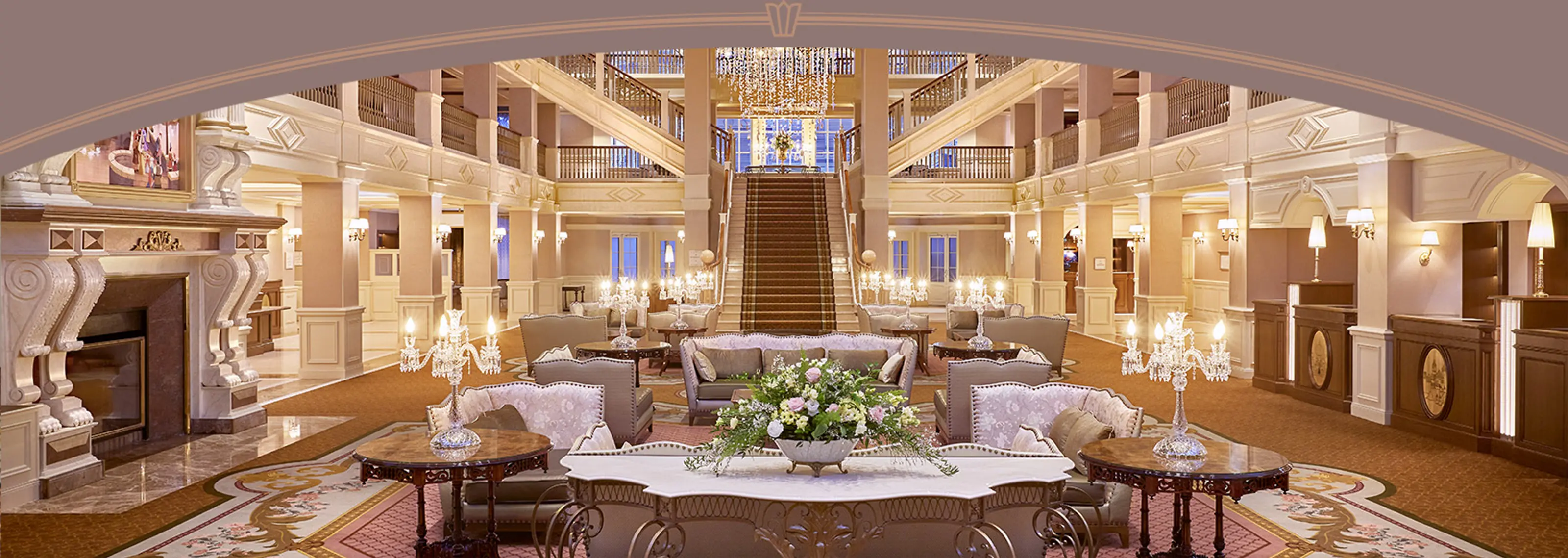 Lobby van het Disneyland Hotel in Disneyland Paris met kroonluchters, monumentale trap en zithoeken