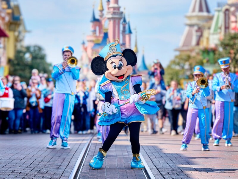 Minnie Mouse loopt over Main Street USA met een marching band achter haar aan