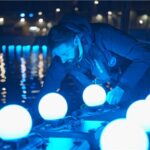 DRONISOS medewerker bereidt verlichte drones voor drone-lichtshow bij wateroppervlak 's nachts