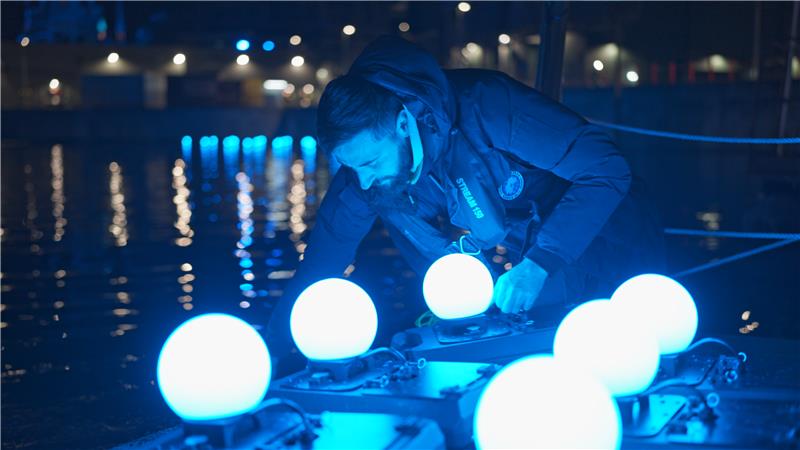 DRONISOS medewerker bereidt verlichte drones voor drone-lichtshow bij wateroppervlak 's nachts