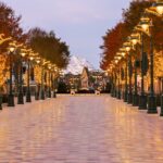 Verlichte laan met lantaarnpalen en herfstbomen in Arendelle bij schemering in World of Frozen, Disney Adventure World Disneyland Paris