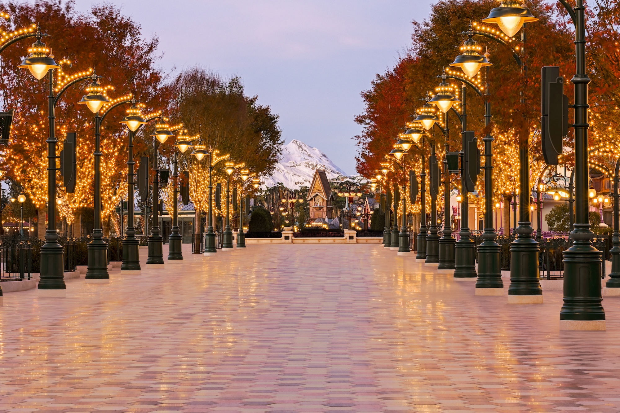 Verlichte laan met lantaarnpalen en herfstbomen in Arendelle bij schemering in World of Frozen, Disney Adventure World Disneyland Paris