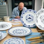 Porseleinschilder bij Royal Delft beschildert borden met Delfts blauwe Disney-patronen in het atelier