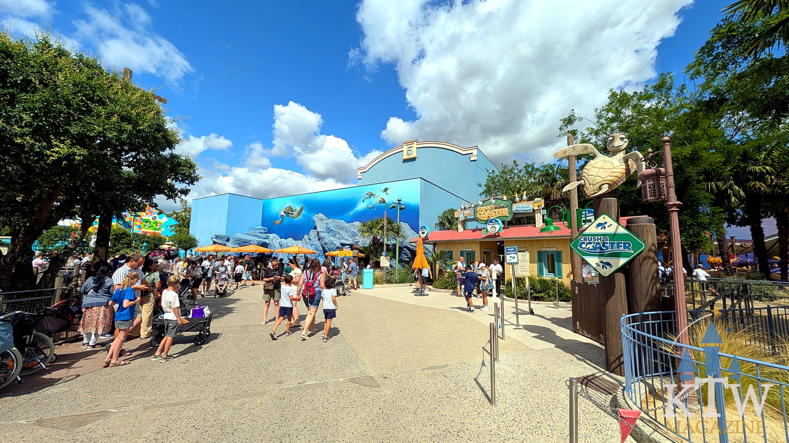 Visitors walk along the path towards Crush's Coaster next to the Finding Nemo building